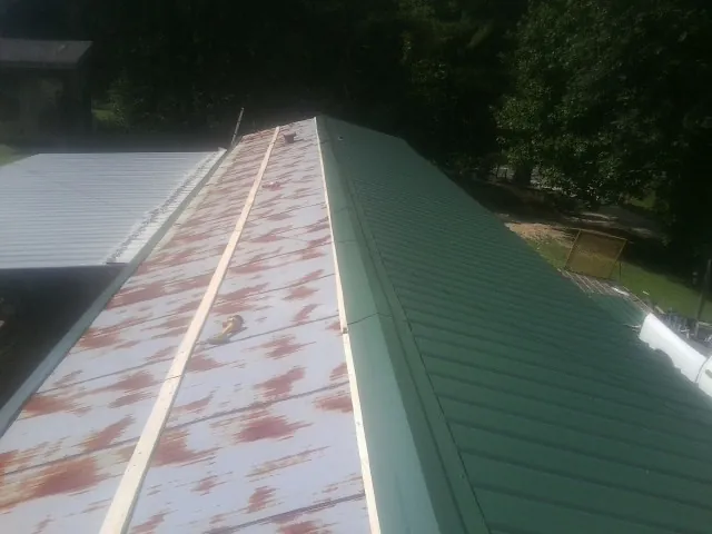Old rusted panels beside newly installed green metal roofing — Wind Damage Roof Repair by Roofing Brothers in Cherokee